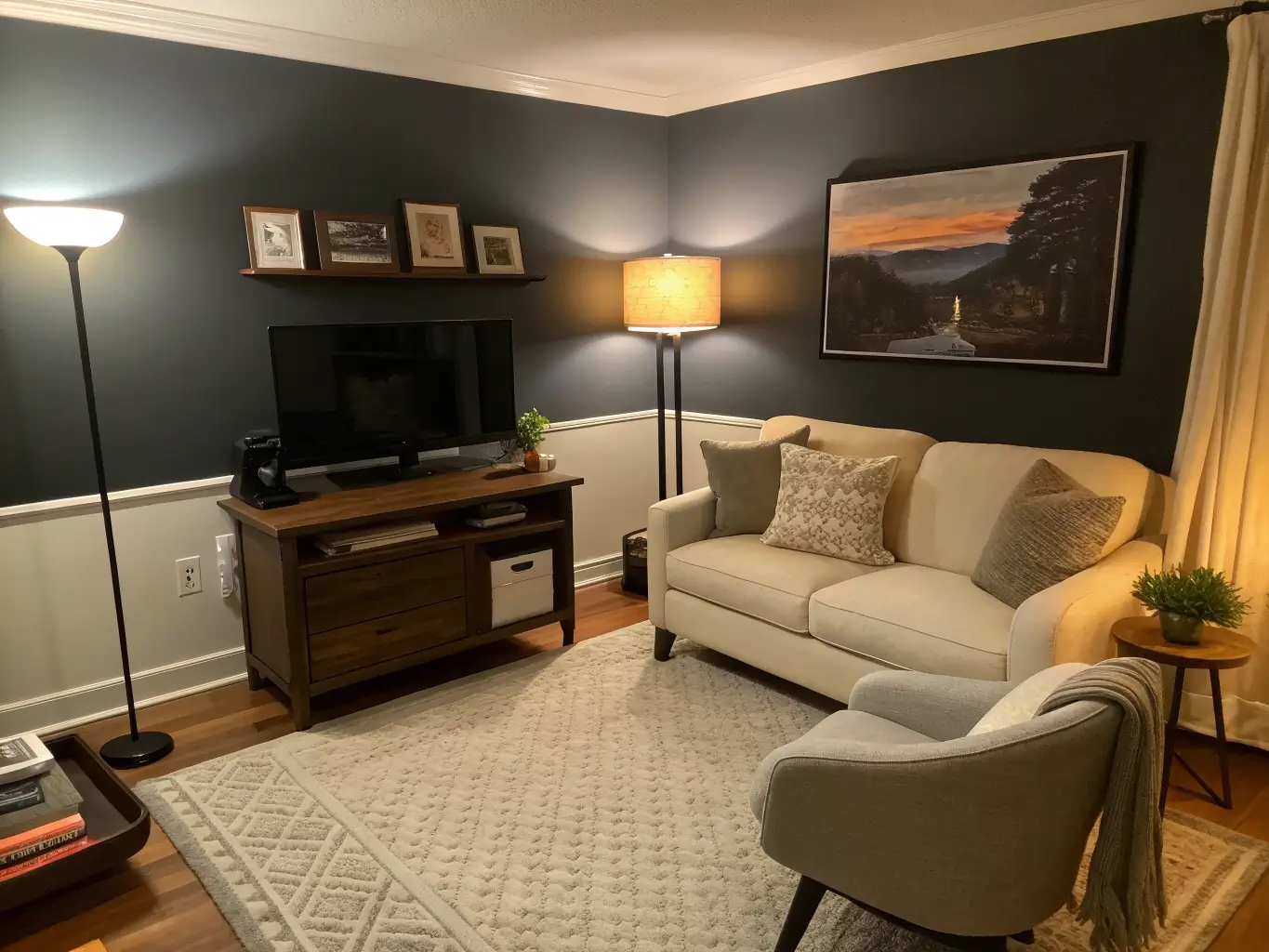 Evening home office-lounge with warm layered lighting, ivory boucle loveseat by glowing floor lamp, charcoal TV wall, taupe rug, and side table with book and plant.